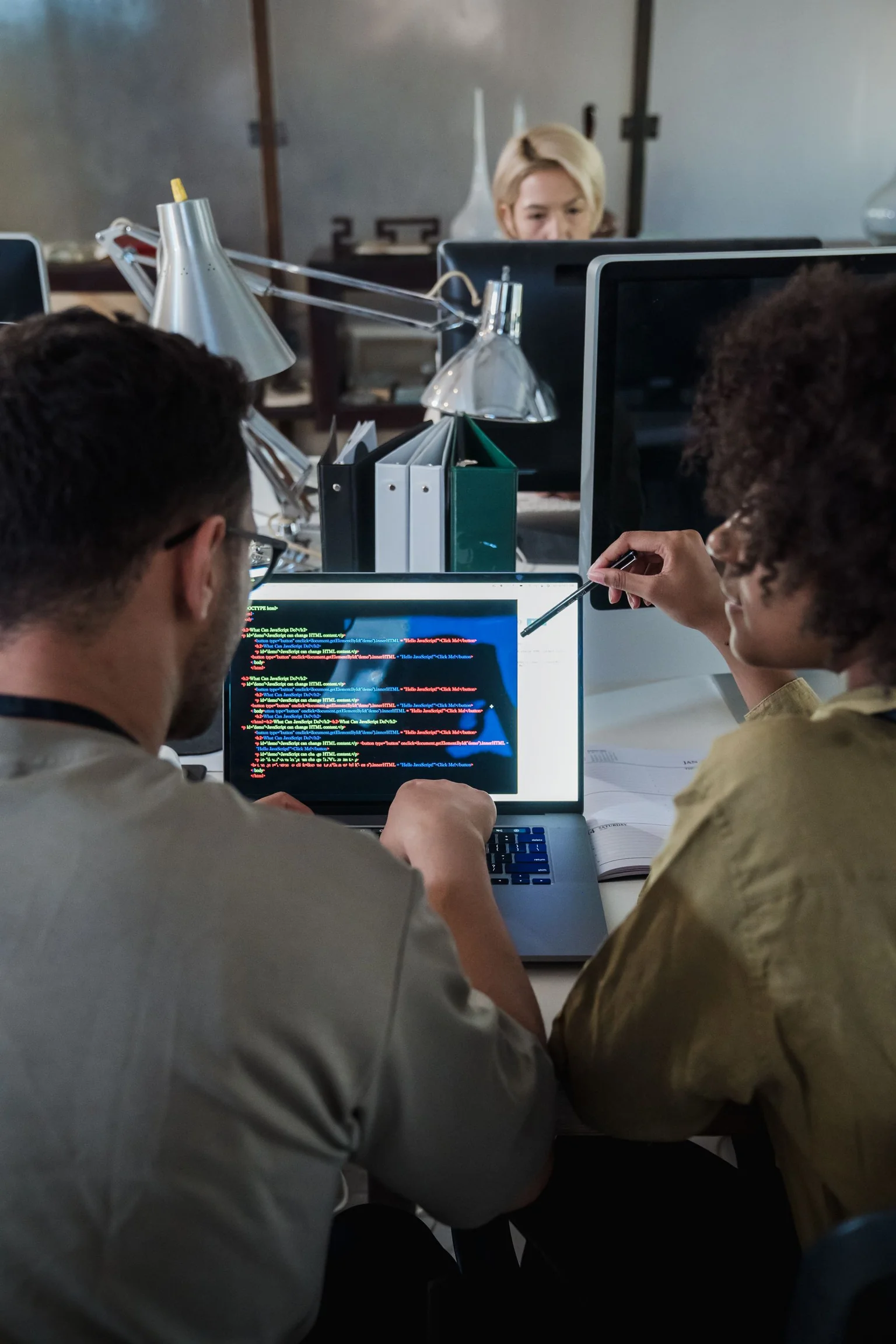 Two developers reviewing software code together on a laptop.